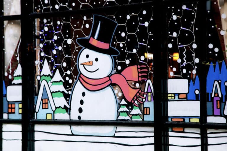 Colorful snowman holiday window display with festive winter scene and Christmas decorations.