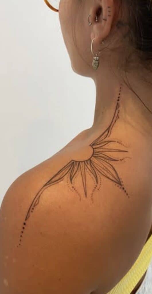 Detailed black ink flower tattoo on woman's shoulder and neck area.