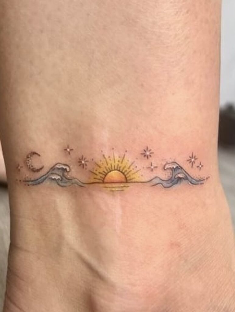 Sunset wave tattoo with stars, moon, and sun design on skin for ocean lovers.