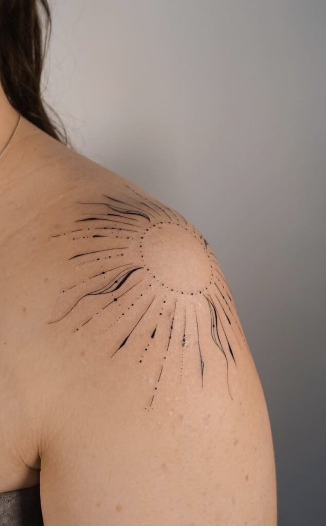 A close-up of a shoulder tattoo with artistic black ink lines and dot work, body art.