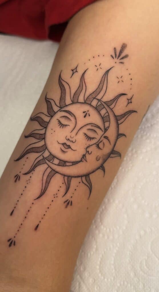 Delicate black line sun and moon tattoo with faces, stars, and decorative dots.