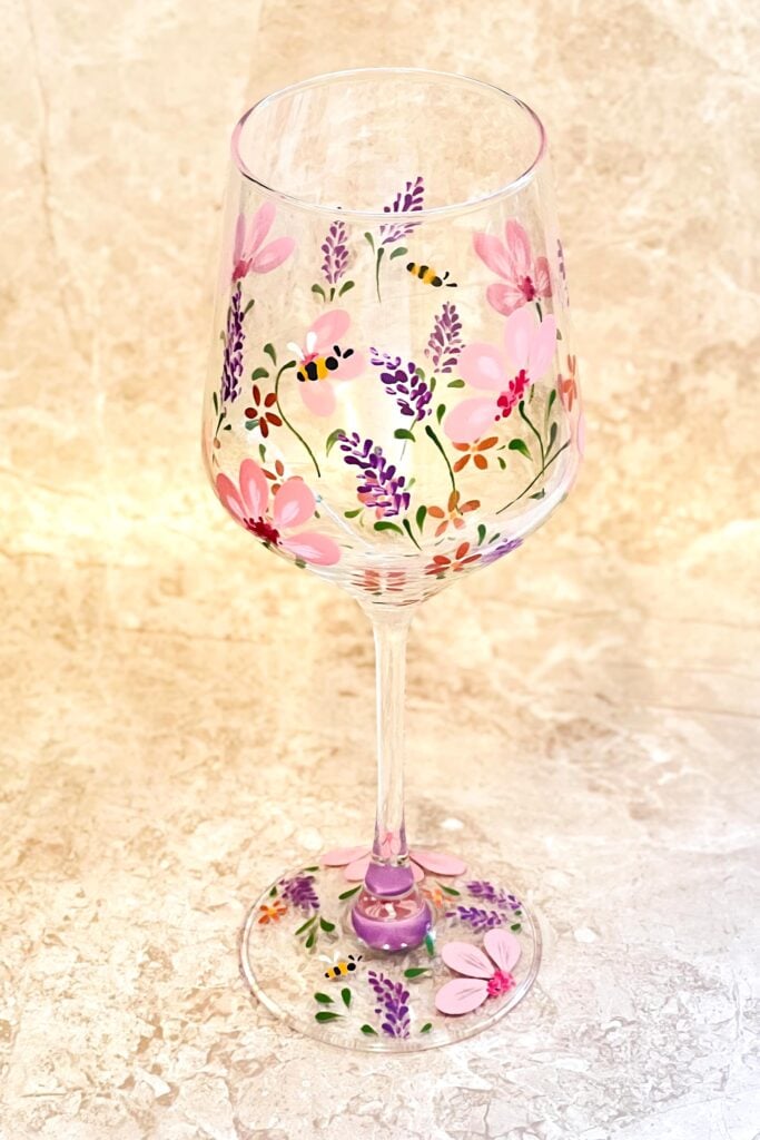 Elegant wine glass with hand-painted pink, purple, and yellow floral designs.