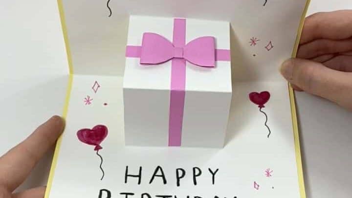 Open birthday card with pink gift box illustration and 'Happy Birthday' message.