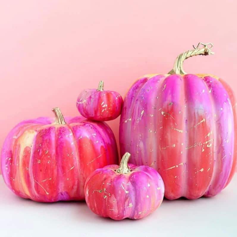 Colorful pink pumpkins with gold accents on a pink background for fall decor.