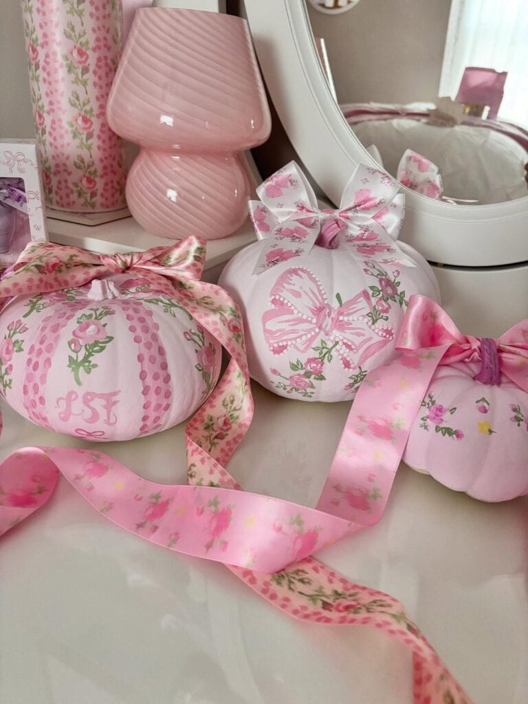 Decorative pink pumpkins with ribbons and floral patterns for fall.