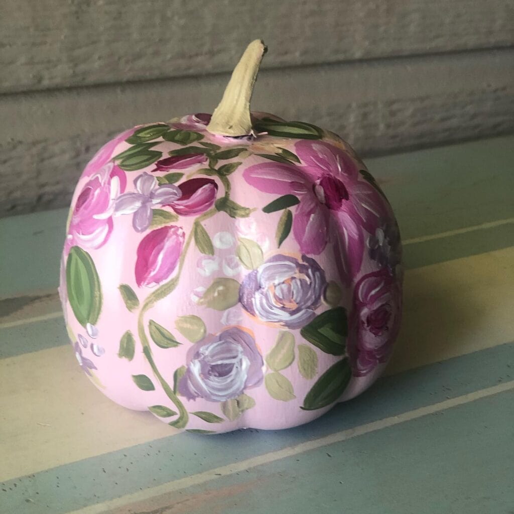 Pink pumpkin with floral painted design for fall decor.