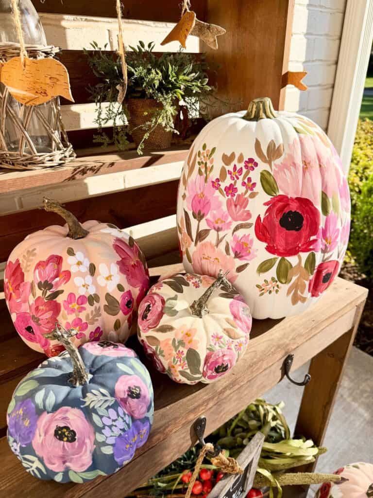 Colorful painted pumpkins with floral designs for autumn decor.