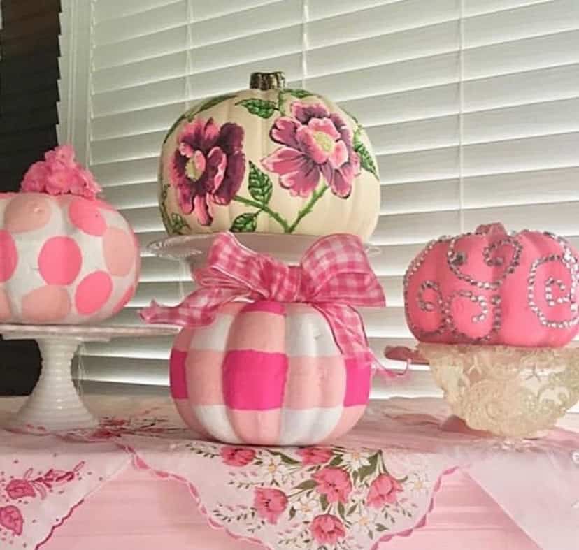 Pink and floral decorated pumpkins for fall decor on a pink table.
